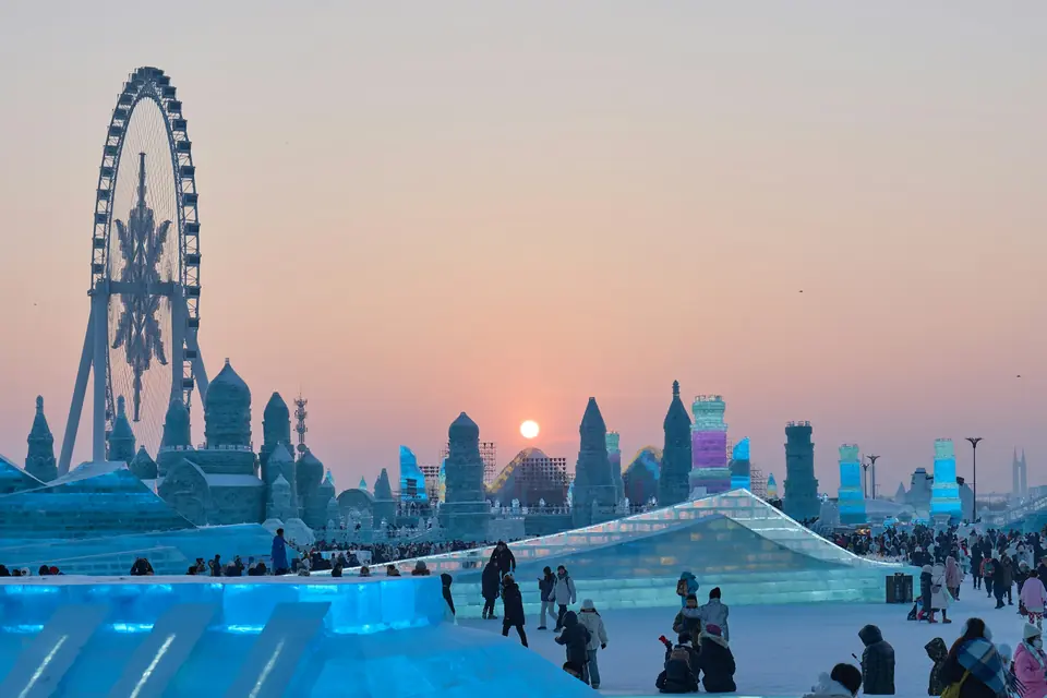 Ice buildings and the Ferris wheel at Harbin Ice and Snow World at sunset