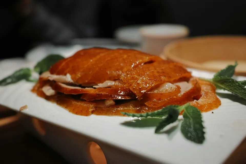 Sliced Peking duck with crisp lacquered skin on a white plate